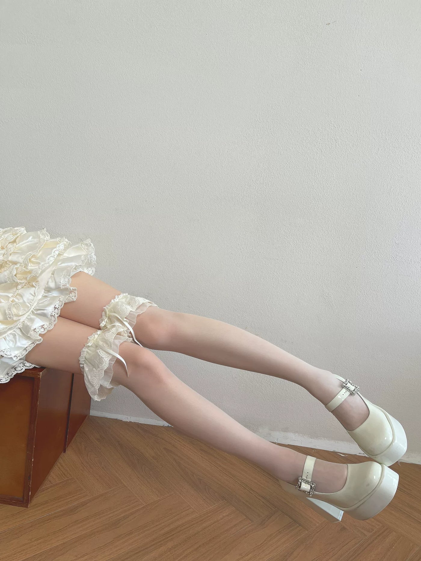 White over-the-knee socks with layered ruffles and scalloped lace edging worn with white platform shoes.