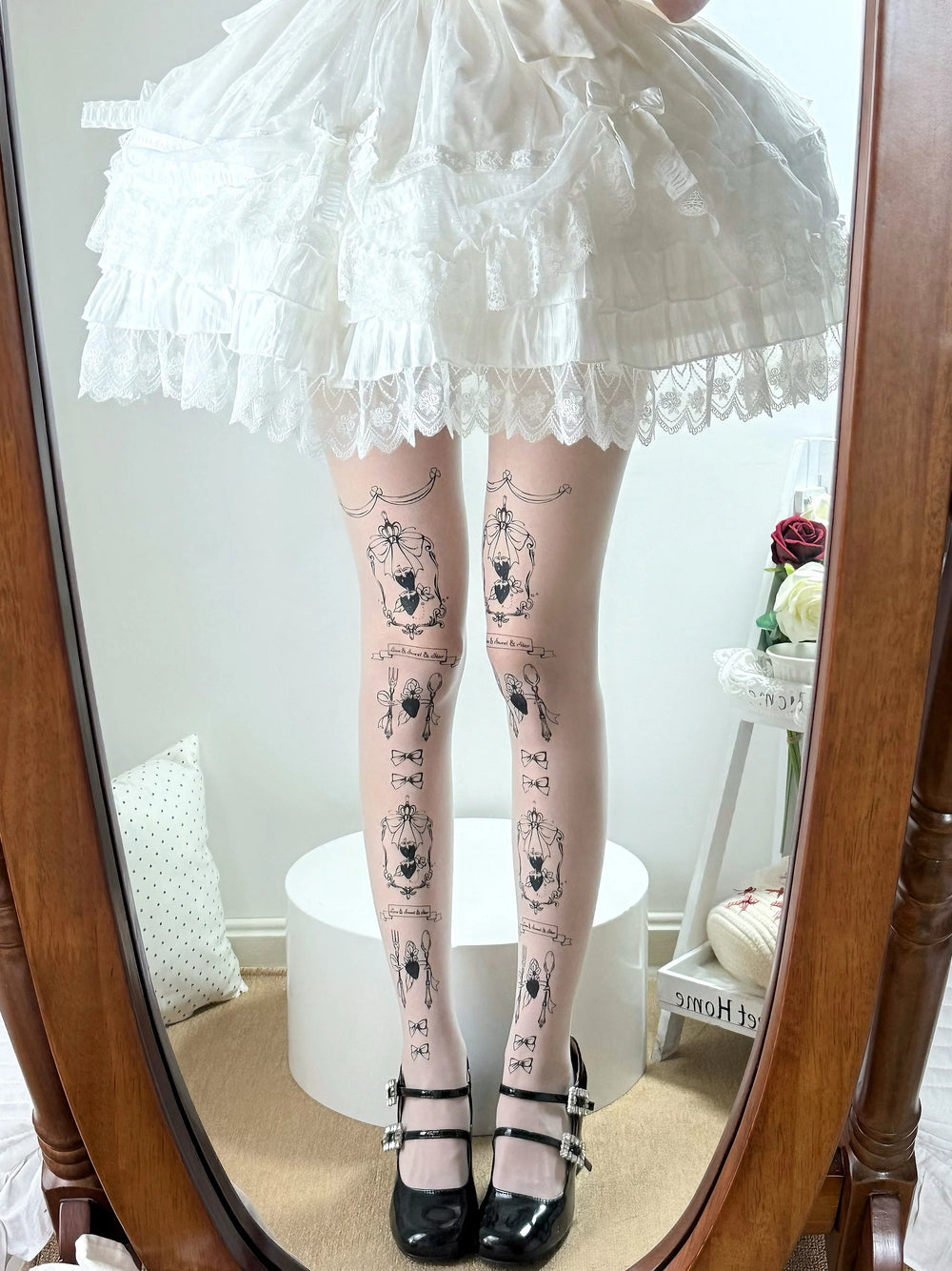 White printed tights with framed bow motifs styled beneath a layered white Lolita skirt.