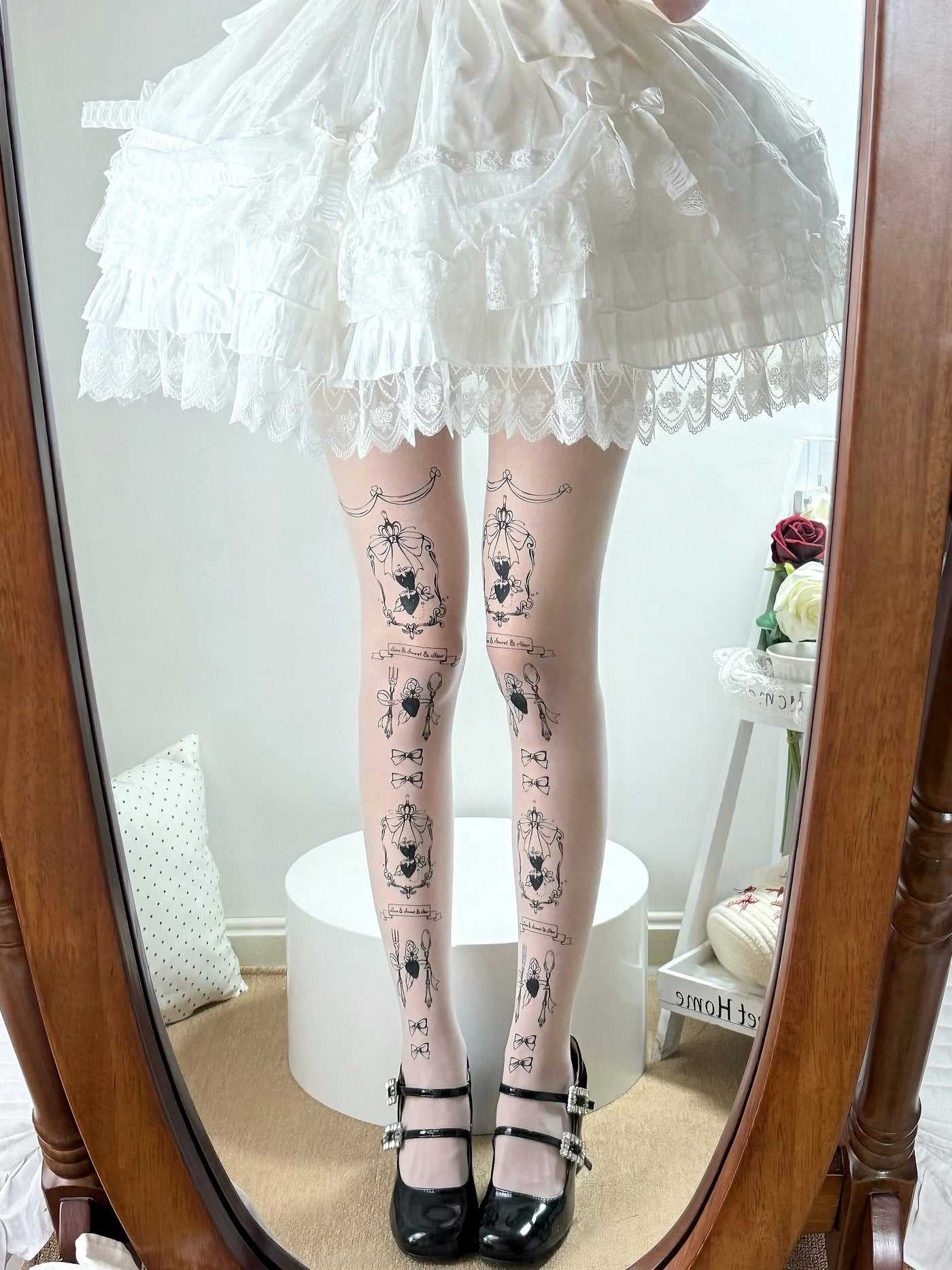 White printed tights with framed bow motifs styled beneath a layered white Lolita skirt.