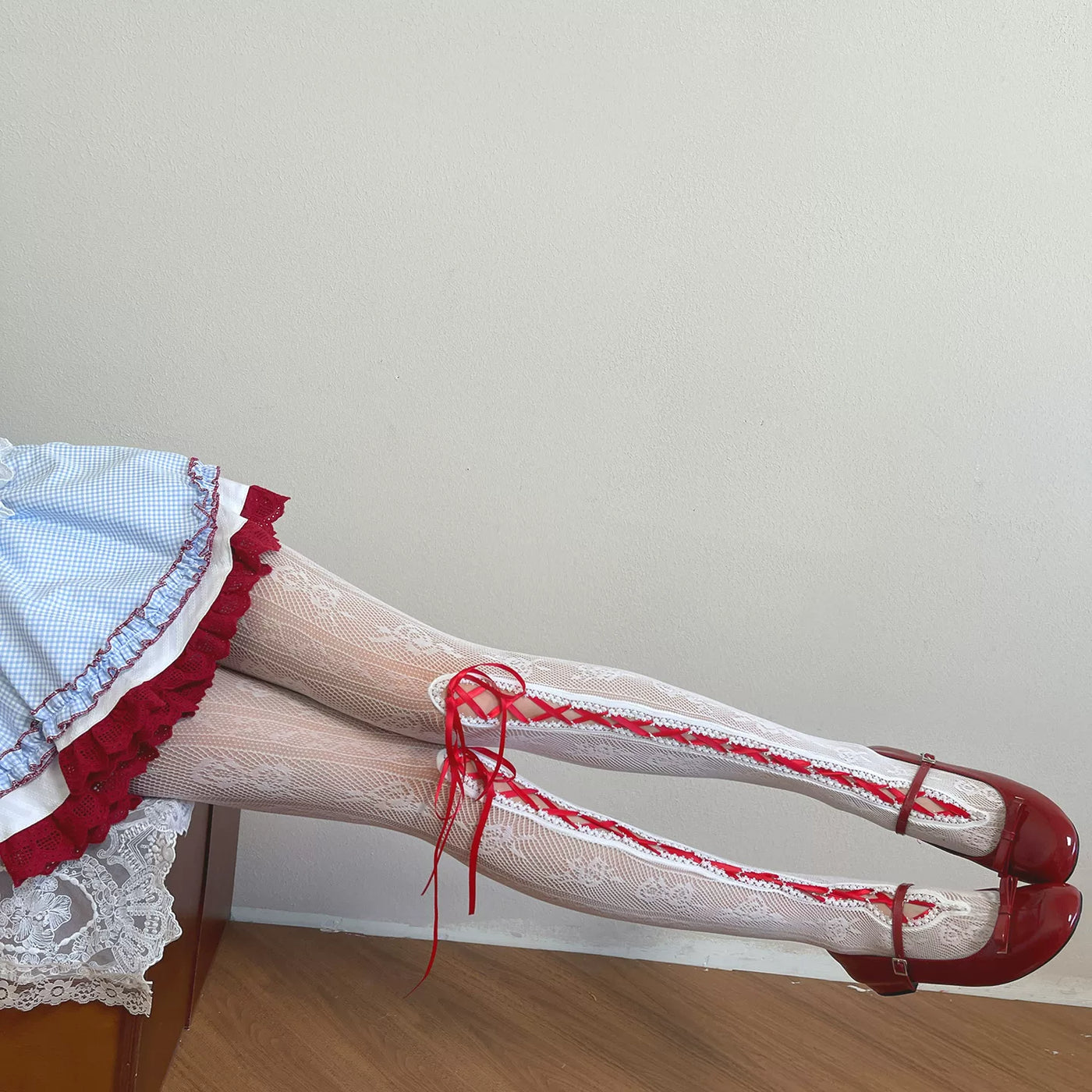 White lace tights with pink ribbon lacing shown on a model.