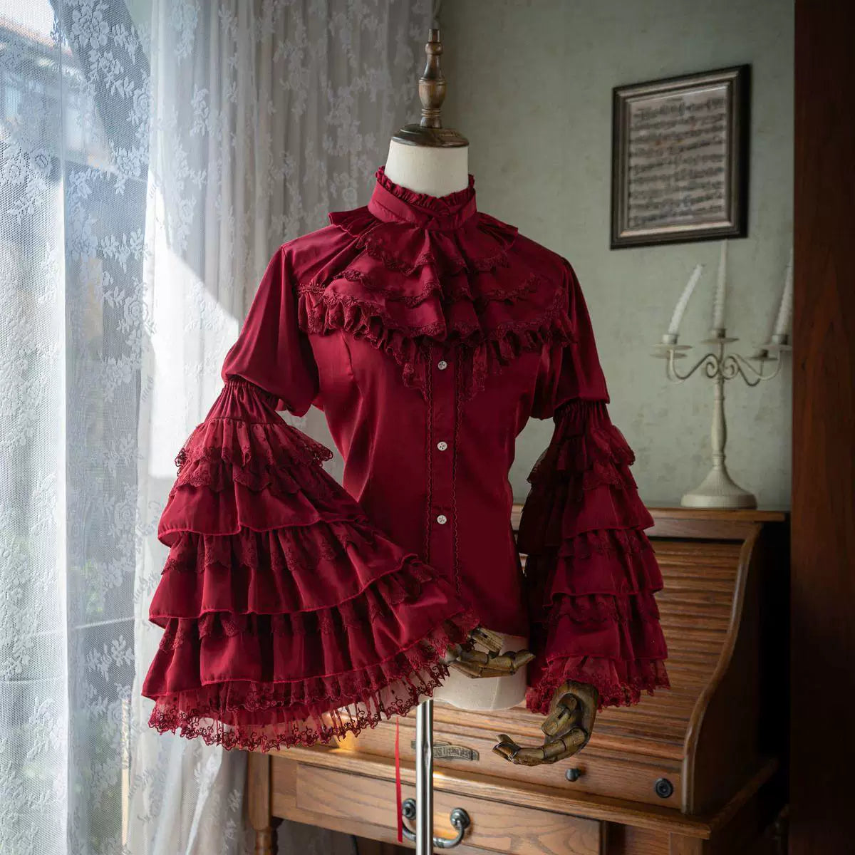 Black and wine-red layered ruffle blouses displayed on dress forms.