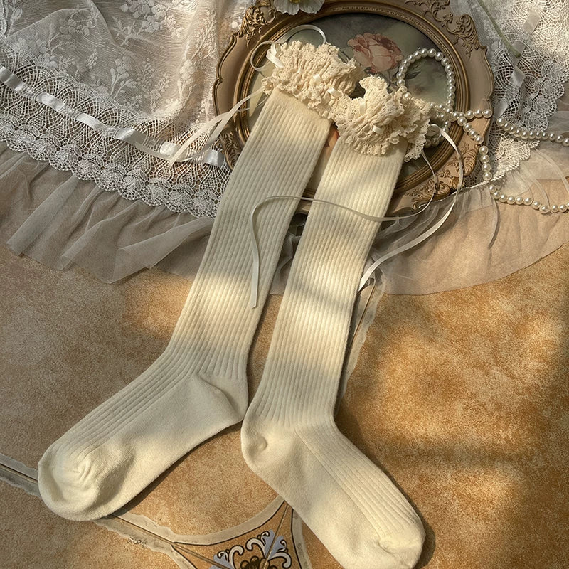 Ivory slouch boot socks with lace cuffs and ribbon ties styled with plush shoes