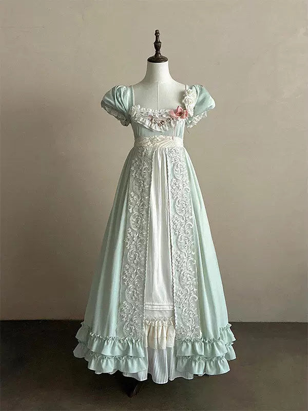 Pale green empire-waist one-piece dress with white lace panels and layered ruffles on a mannequin.
