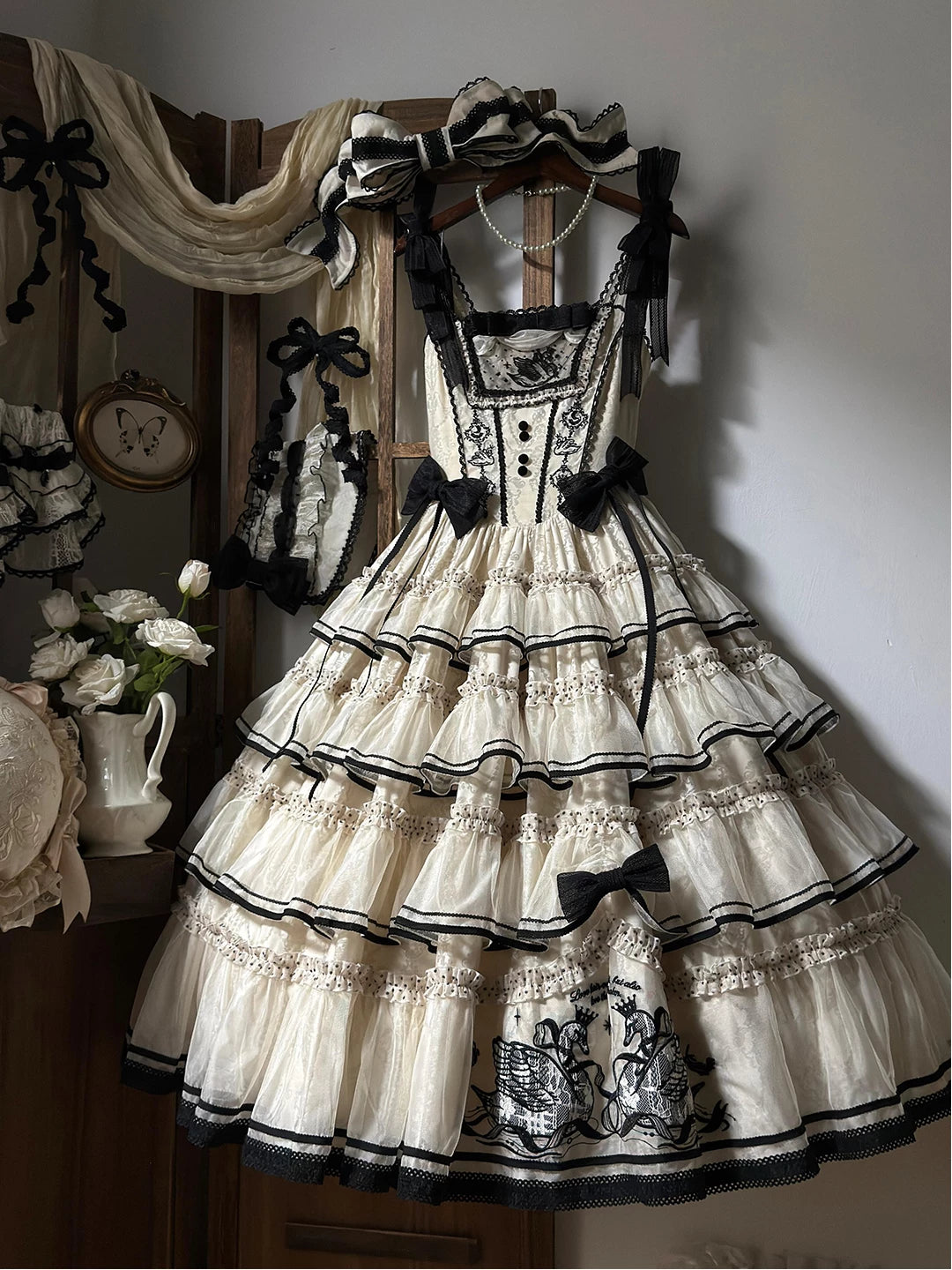 Ivory and black Creamy JSK dress with tiered ruffles, swan embroidery, black bows, and a matching headpiece.