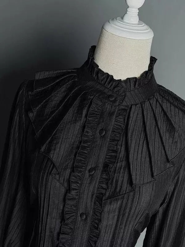 Black long-sleeve blouse with high ruffled collar and flared cuffs on a mannequin.