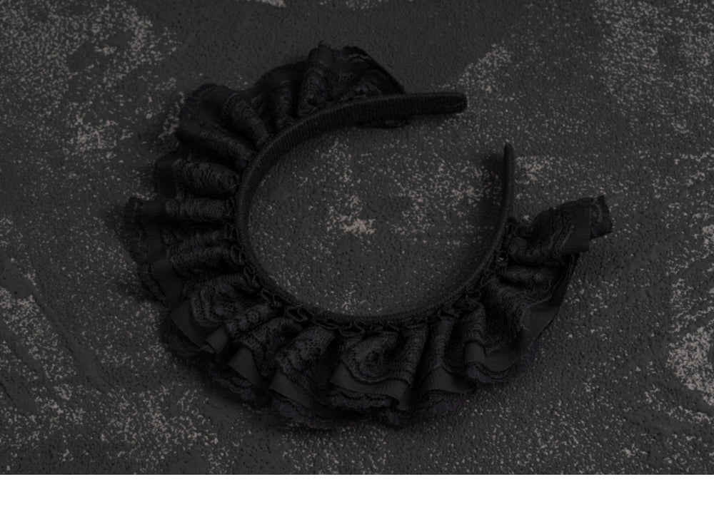 Black lace Gothic Lolita headband photographed on a dark background.