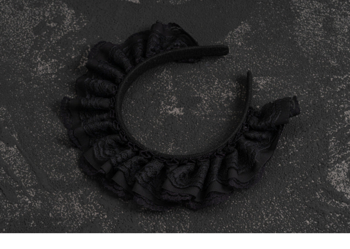 Black lace Gothic Lolita headband photographed on a dark background.