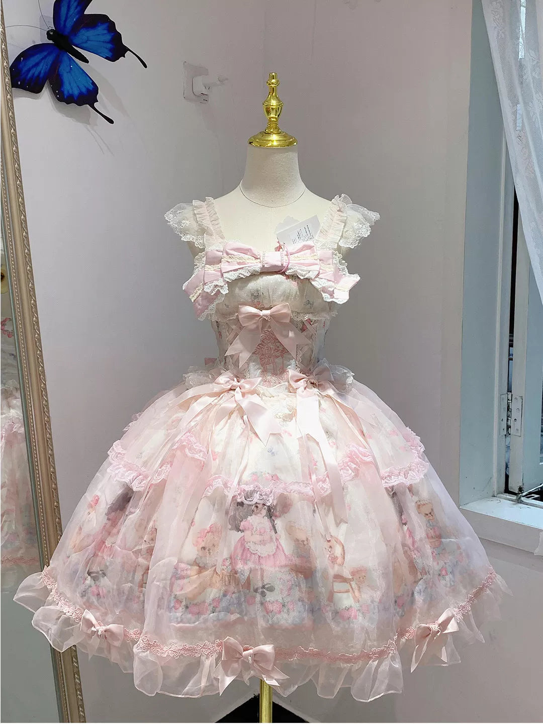 Pastel pink and white bear-print Lolita dress with layered lace skirt and bows displayed on a mannequin.