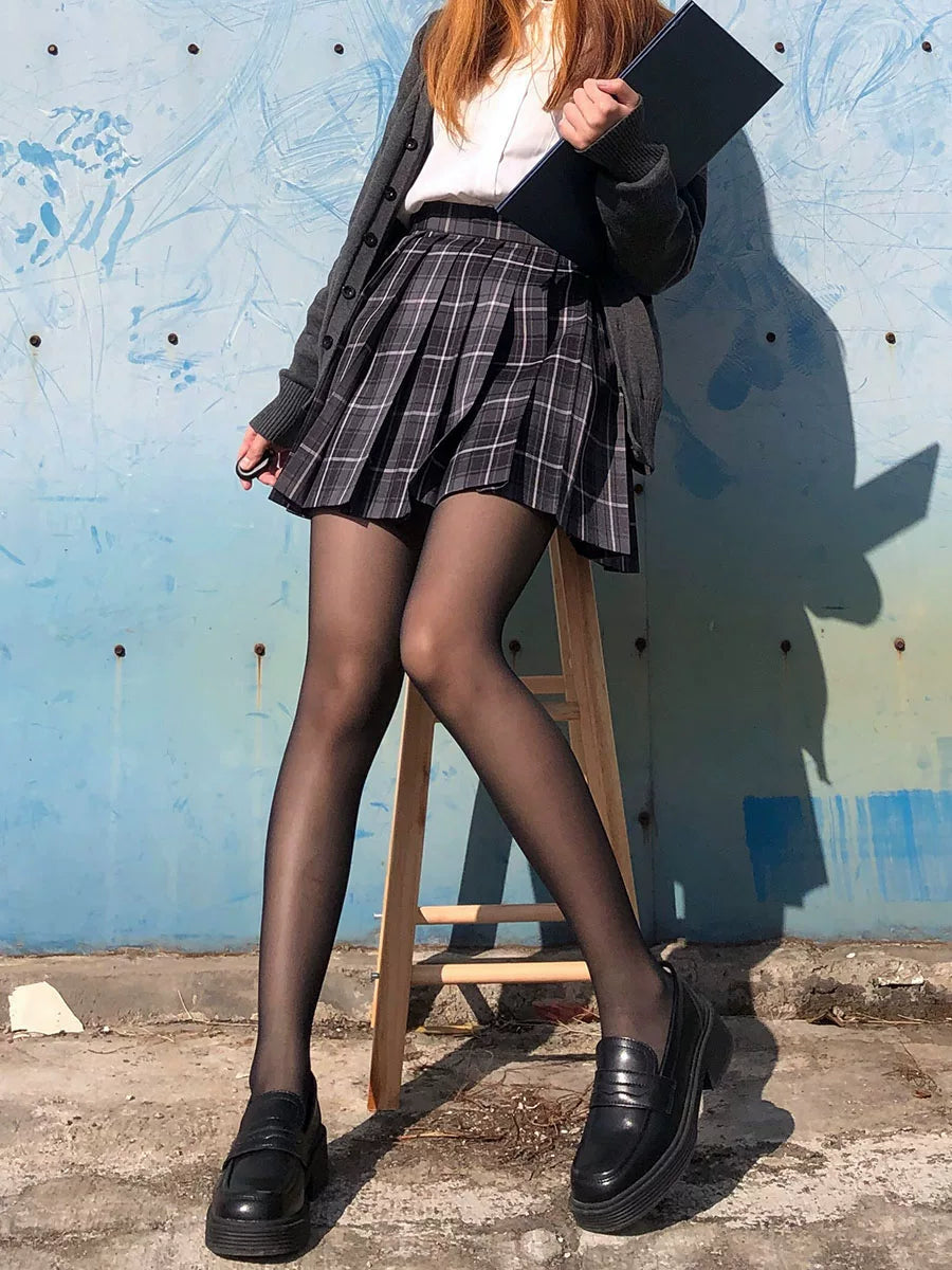 Fine sheer black pantyhose styled with a plaid skirt and black loafers