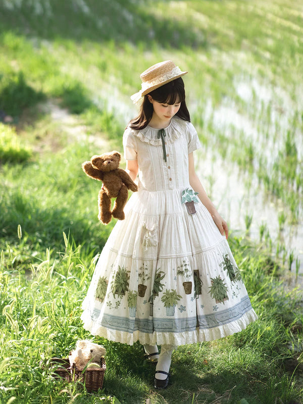 White botanical-print pastoral OP dress worn outdoors with a straw hat.