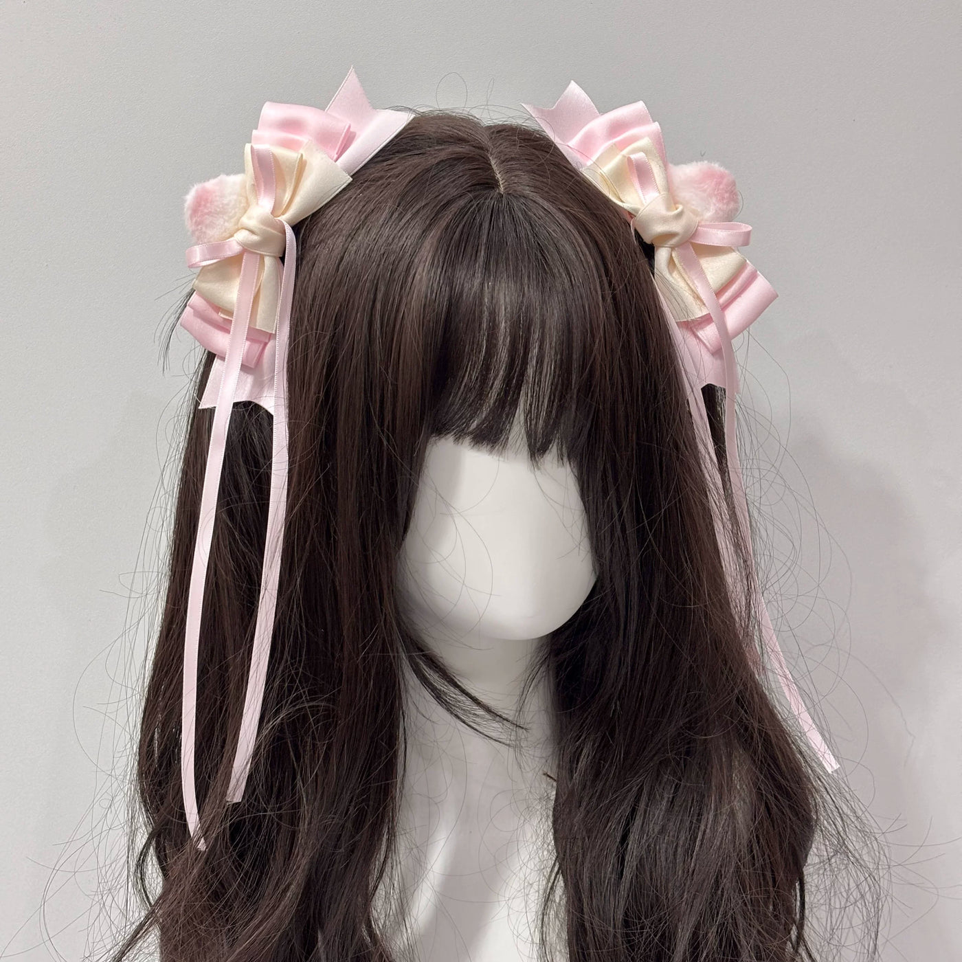 Pink and cream layered bow side hair clips with trailing ribbons on a mannequin