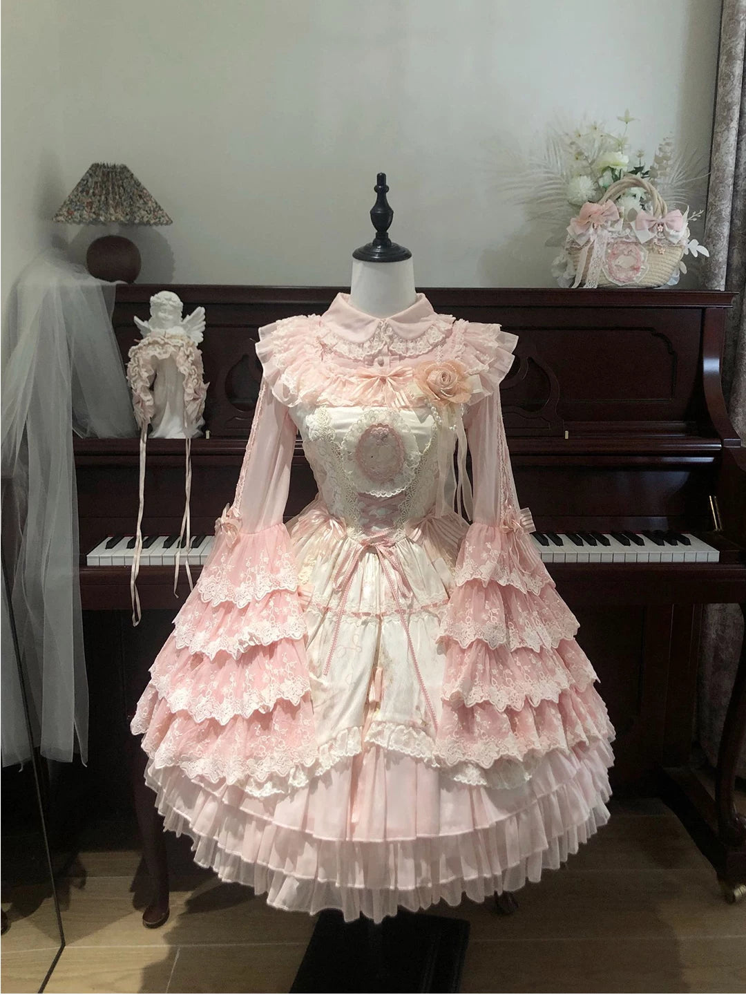 Pink hime-sleeve JSK dress set displayed on a mannequin in front of a piano
