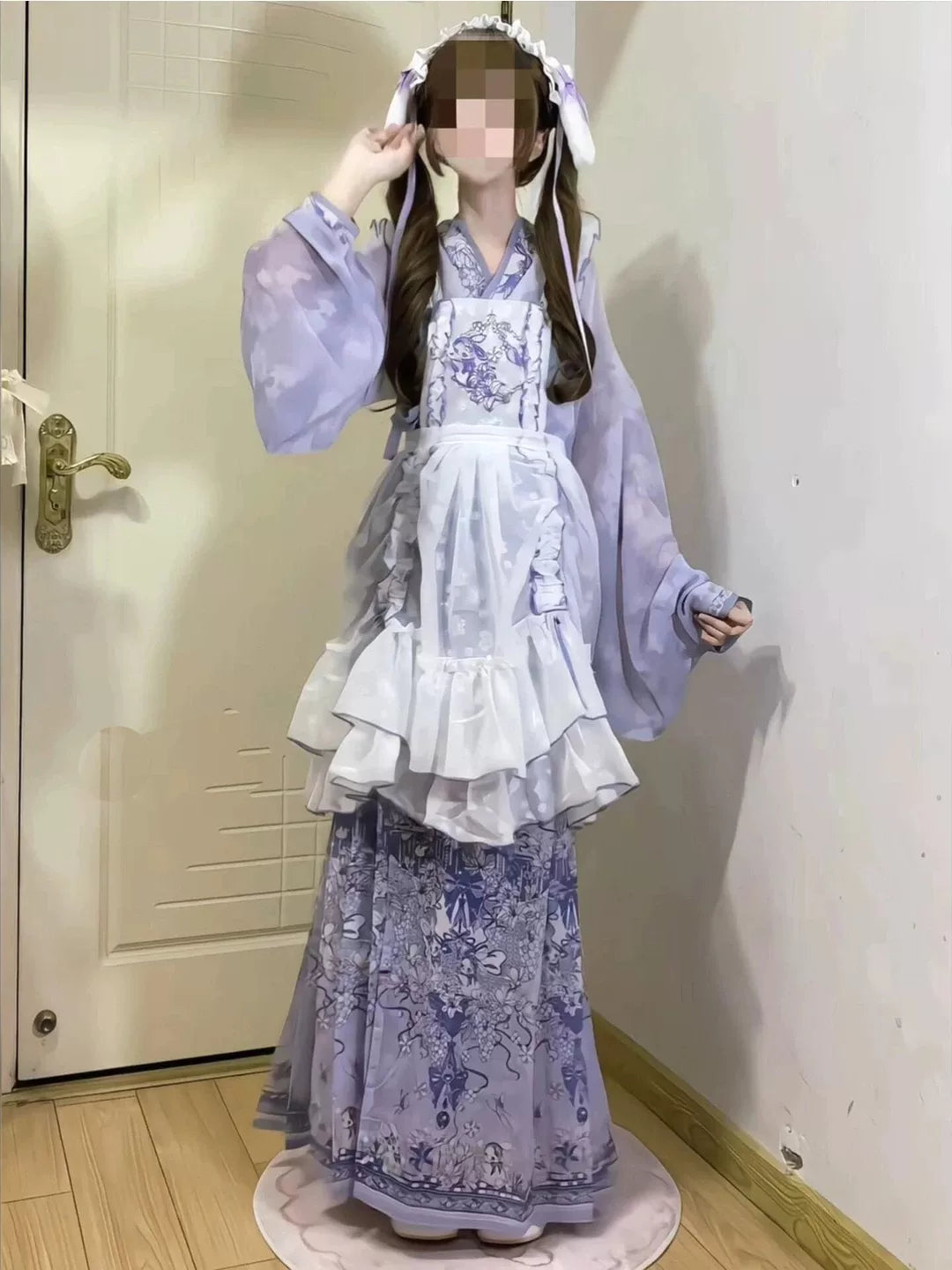 Close-up of white ruffled apron and light lavender outer robe with blue floral embroidery