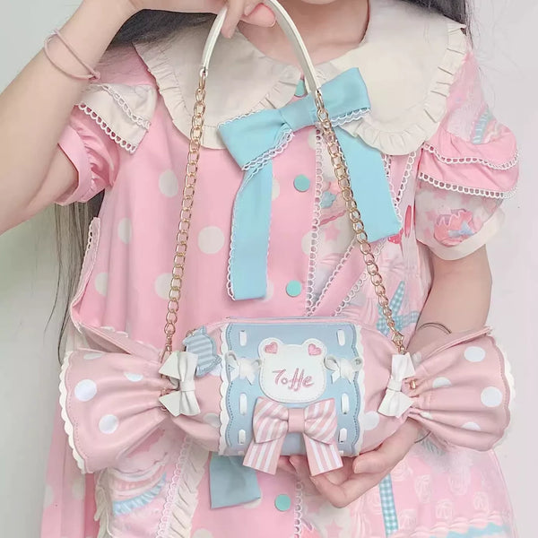 Powder blue and pink crossbody bag with oversized bows, chain strap, top handle, and embroidered front patch