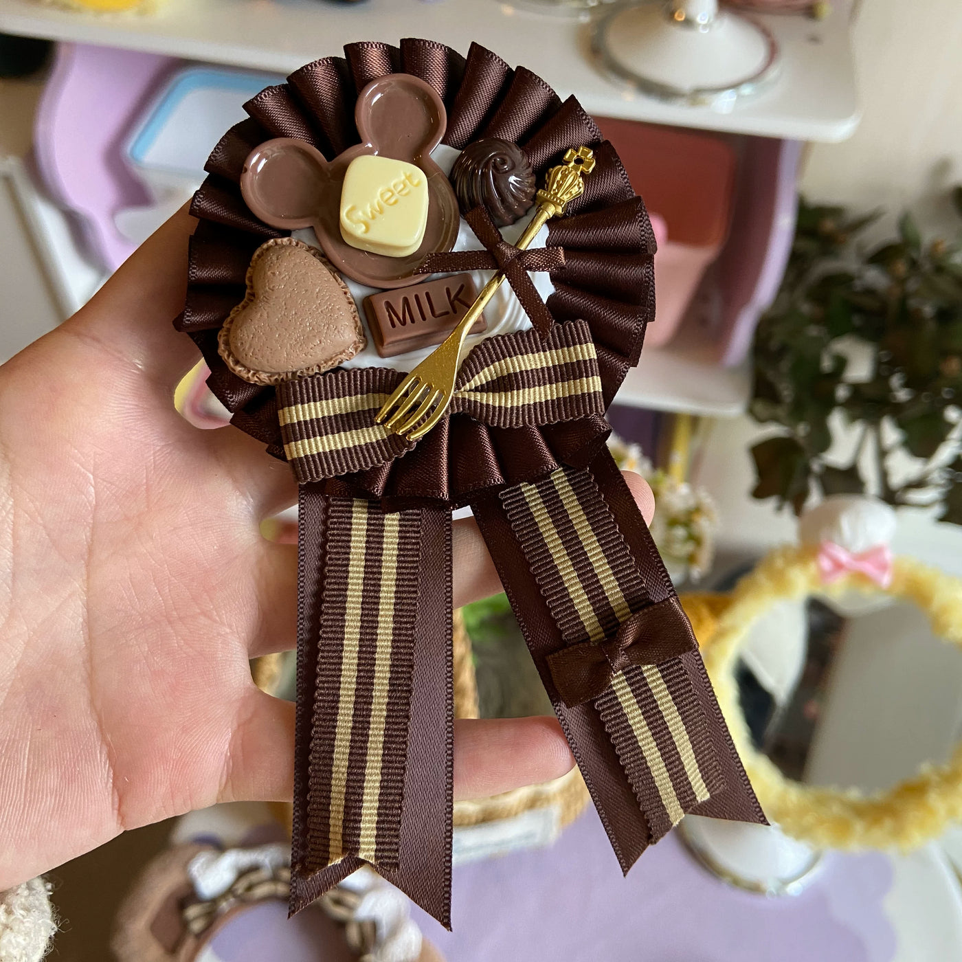 Chocolate-brown bow accessory with dessert charms, striped ribbons and a gold fork detail.