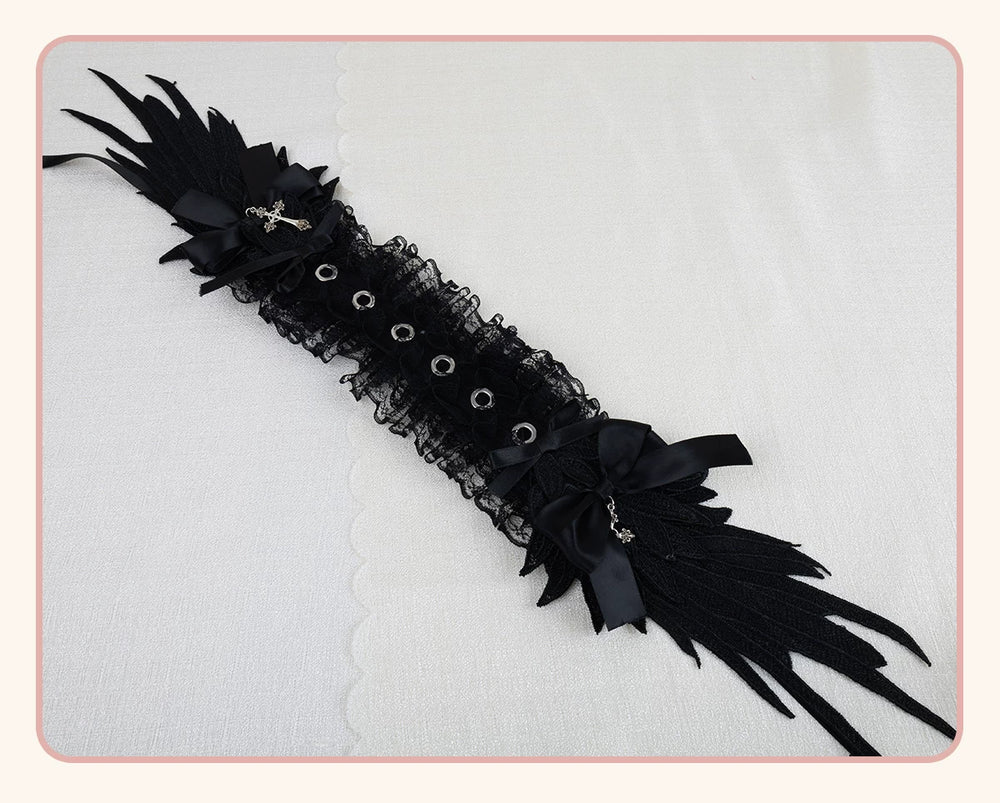 Black wing-and-cross lace headband with bows, eyelets, and long ribbon ties laid flat