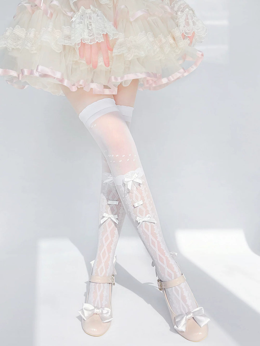 White and black over-the-knee socks with diamond patterns and bows shown worn