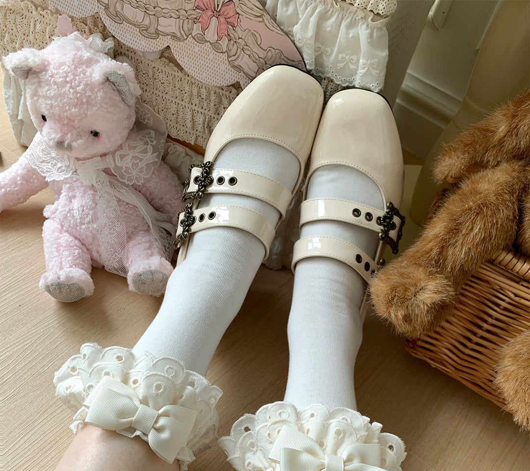 Lace-trimmed socks with bows in multiple colours arranged beside red shoes on a wooden floor.