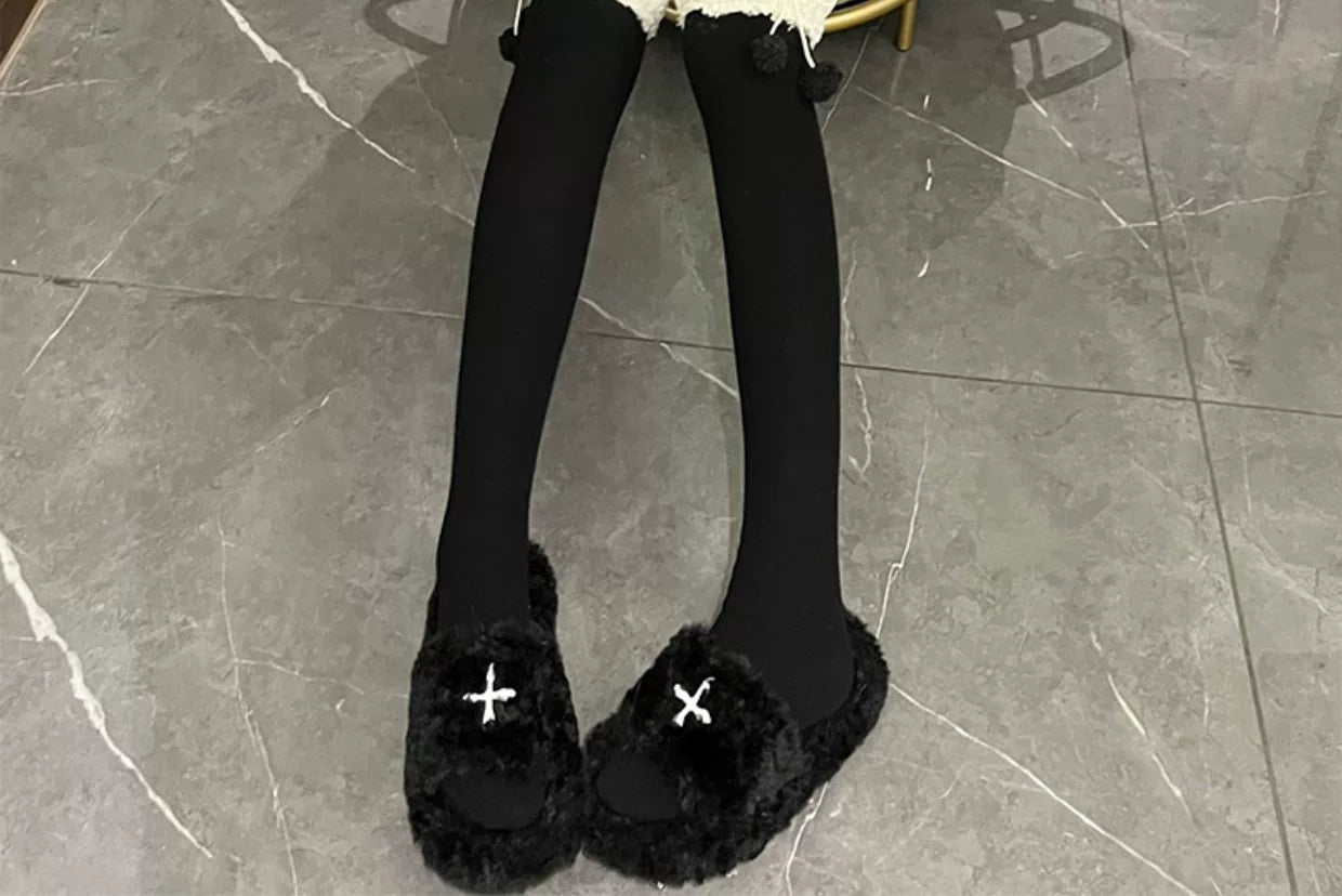 Black thigh-high socks with plush cuffs and pom-pom details shown with black footwear.
