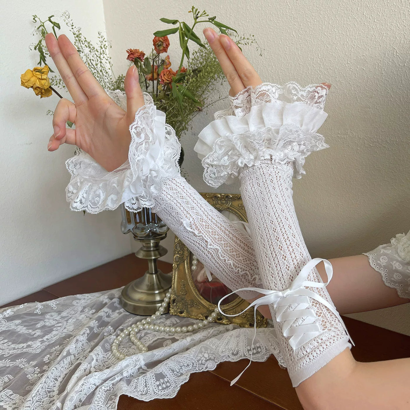White lace arm sleeves with layered ruffles and ribbon ties, shown worn beside a lace Lolita coordinate.