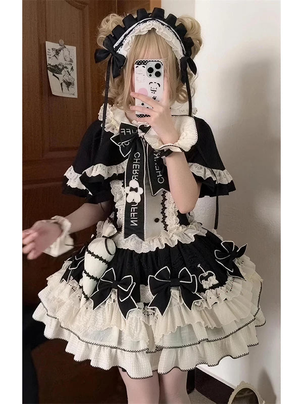 Model wearing a black-and-white ruffled JSK dress with a cape and large bows.