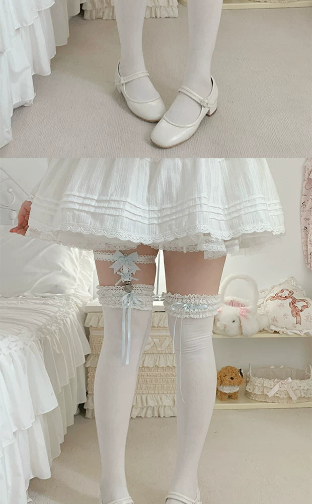 White, pink and black lace sock garters with bows and silver heart clips arranged on a lace cloth.