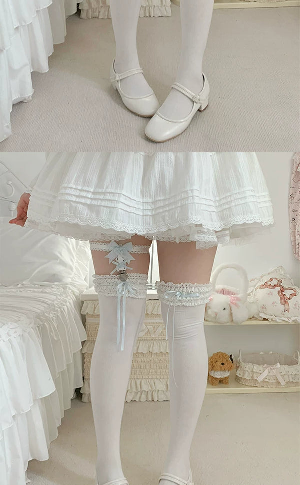 White, pink and black lace sock garters with bows and silver heart clips arranged on a lace cloth.
