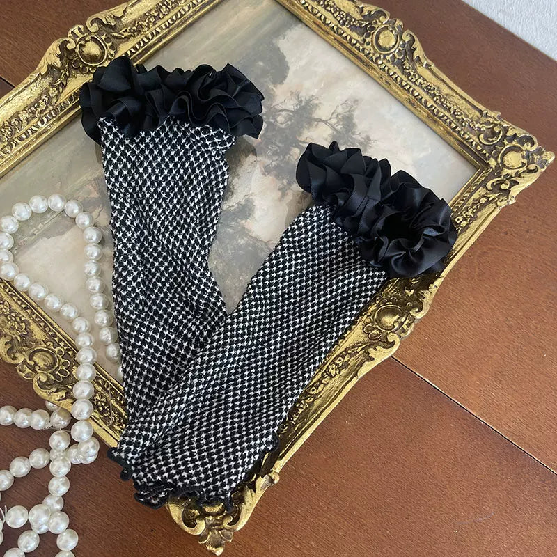 Black-and-white houndstooth arm warmers with fishnet panels and layered ruffle trim.