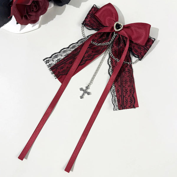 Red lace bow pin with chains and cross pendant laid flat