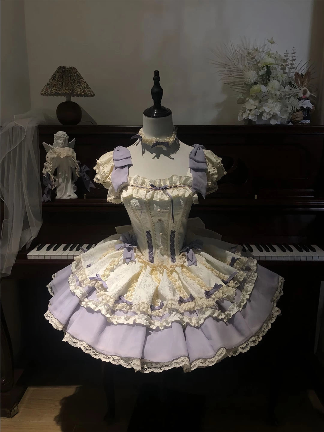 Lavender-and-ivory layered Lolita dress with lace ruffles and lavender bows displayed on a mannequin.