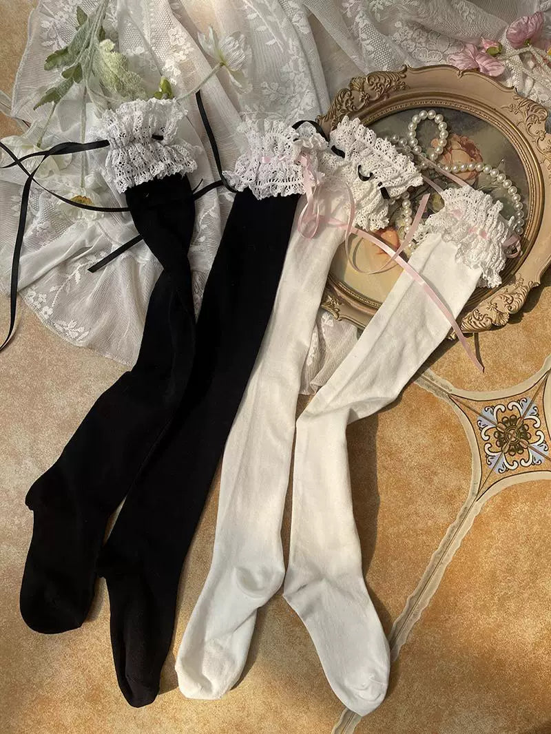 Flat lay of black and white thigh-high socks with lace cuffs and black or pink ribbon ties.