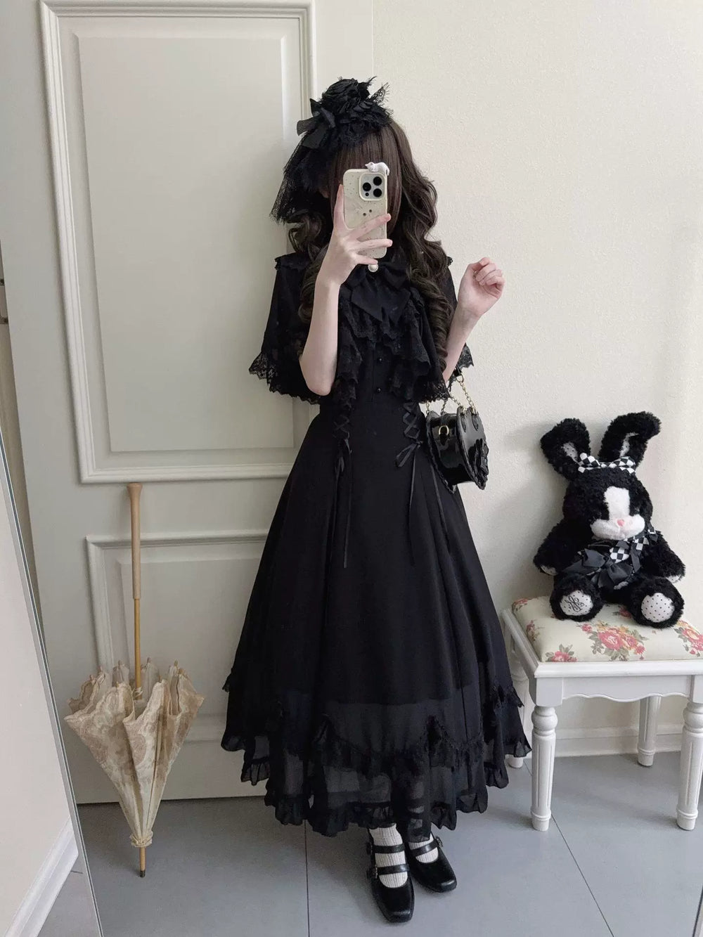 Model wearing a long black lace Lolita dress with a cape collar in a mirror selfie.