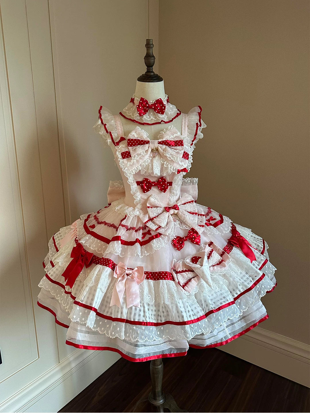 White JSK with red trim, polka-dot bows and layered lace on a mannequin.
