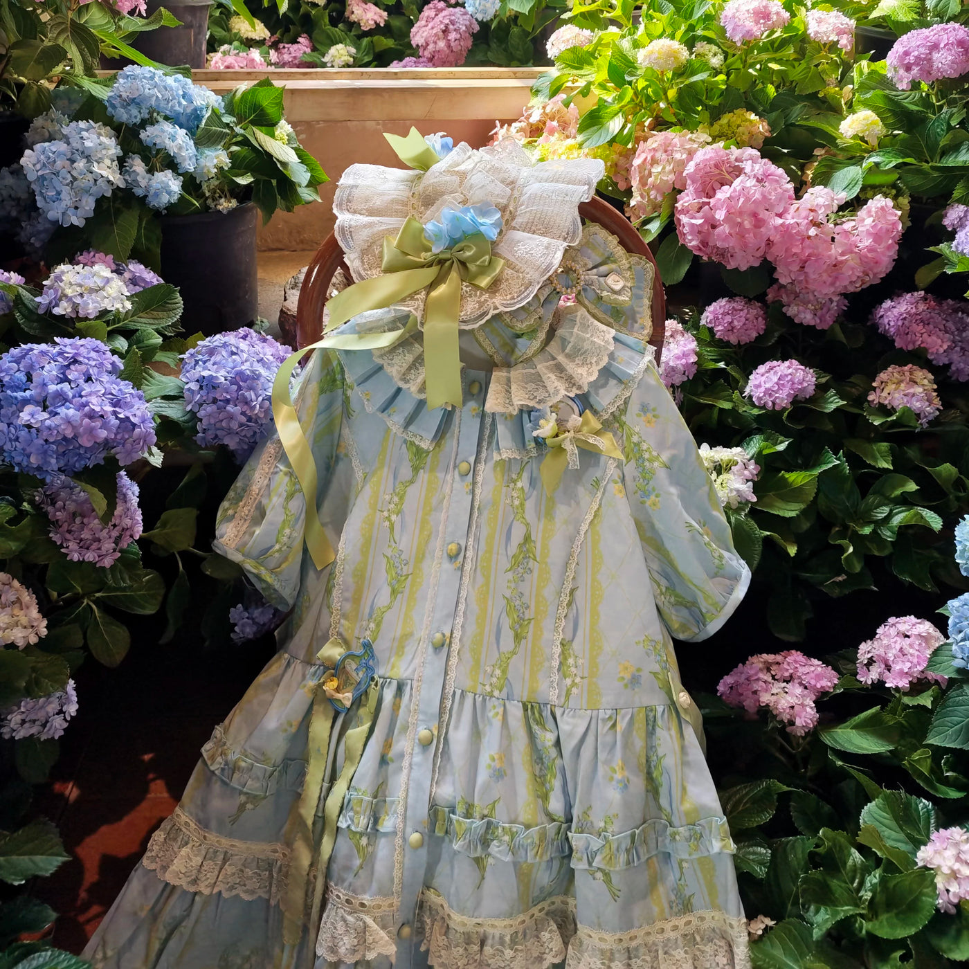 Blue floral Lolita dress with lace ruffles, ribbons and flower accents shown in a garden setting and on a mannequin.