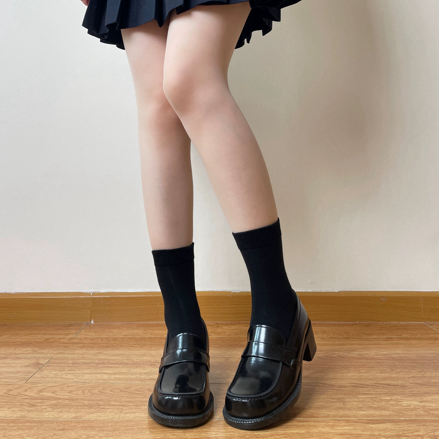 Black and milky white ribbed tube socks styled with plaid and black shoes.