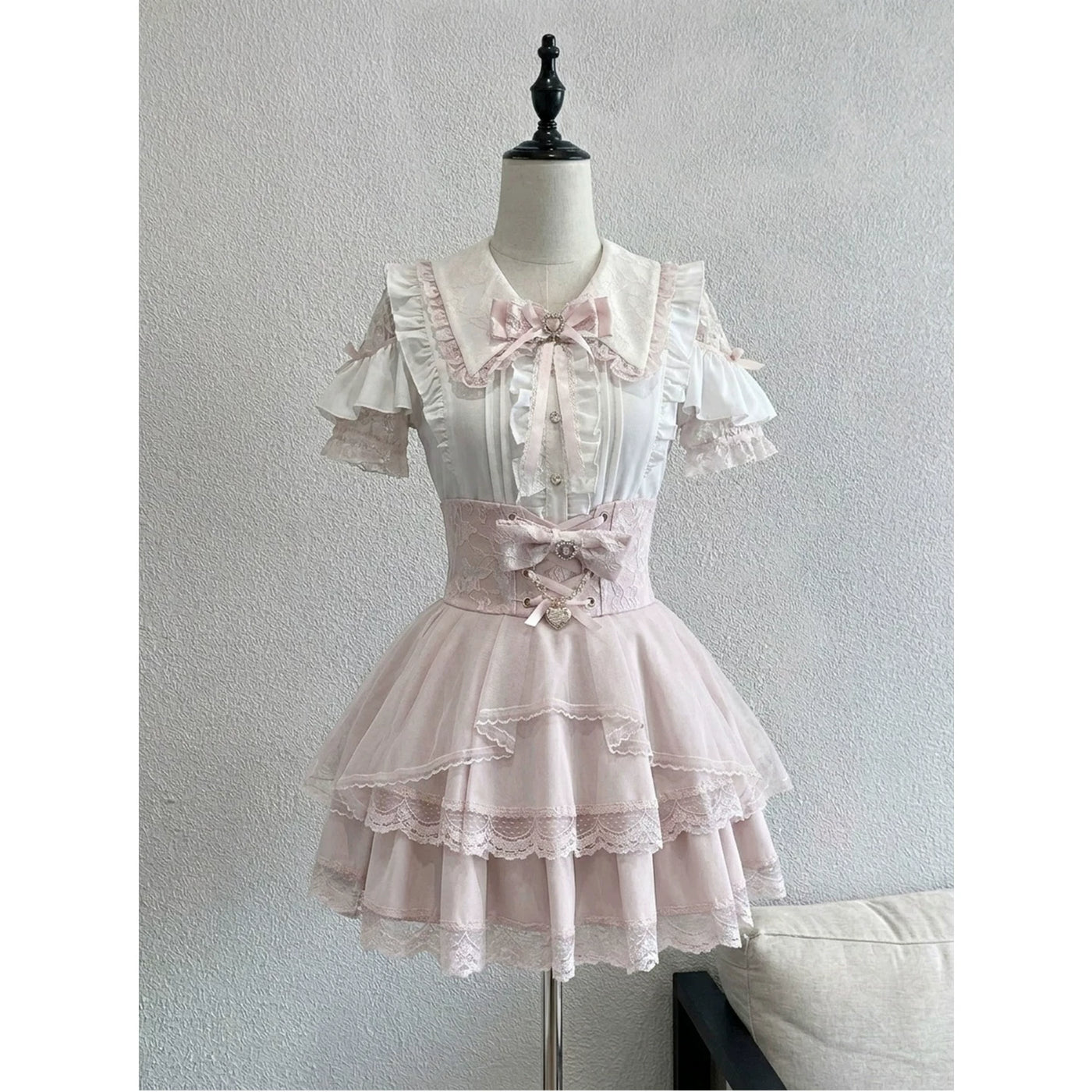 Creamy white short-sleeve blouse and pink high-waisted skirt set with lace trim.