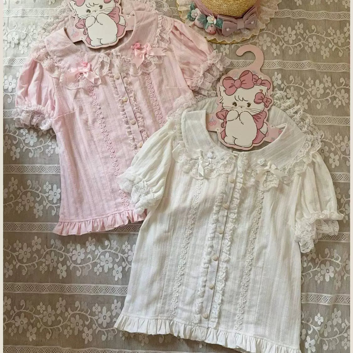Pink lace-trimmed blouse on a hanger with doll collar, bows, fabric flowers and ruffled hem.