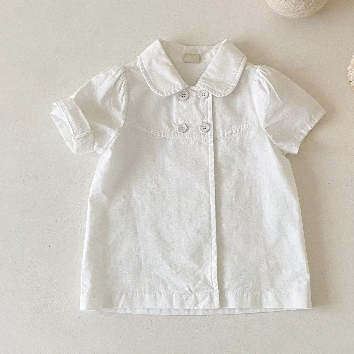 White short-sleeve blouse laid flat with a rounded collar, puff sleeves and four front buttons