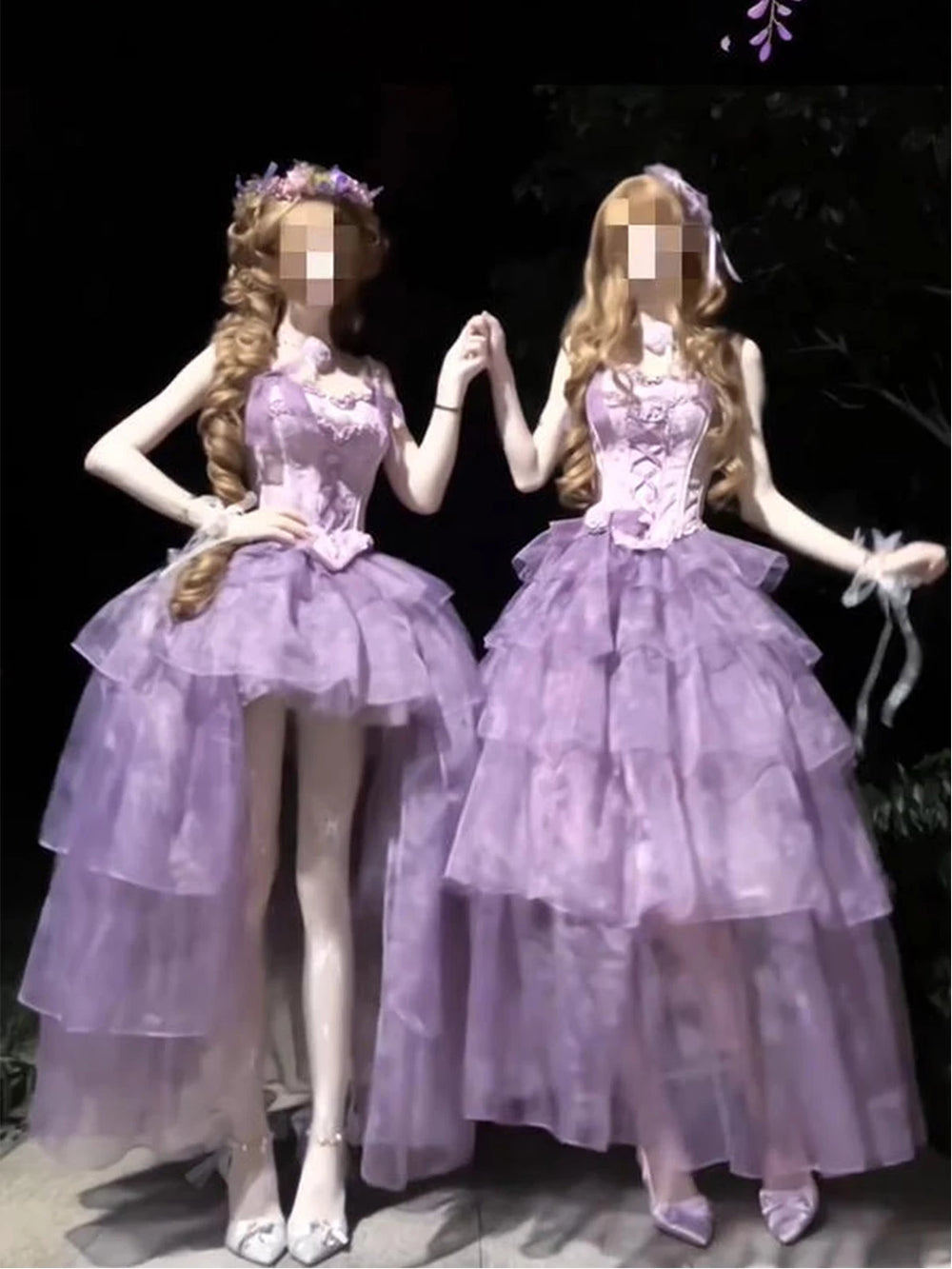 Two purple tiered dresses with lace-up bodices displayed side by side in a dark setting.