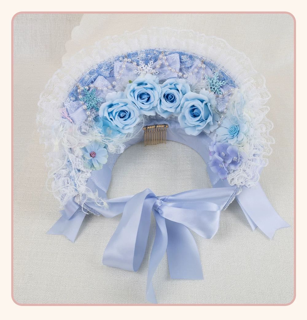 Blue bonnet-style flat hat with pale roses, lace frills, pearl strands and long ribbon ties laid flat.
