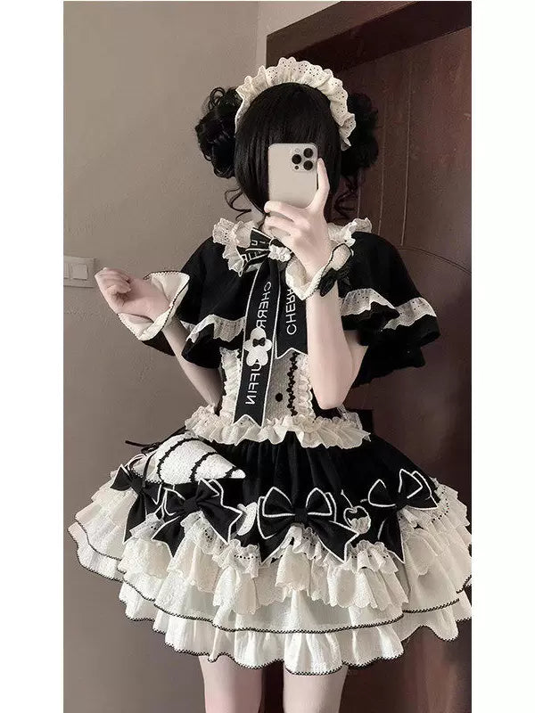 Black ruffled Lolita JSK set with white trim and bows, worn by a model.