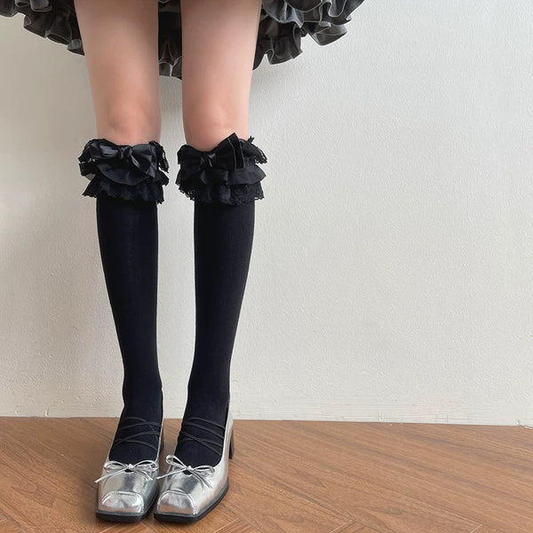 Black and white long-length and mid-calf lace socks with layered trim and bows shown on legs.