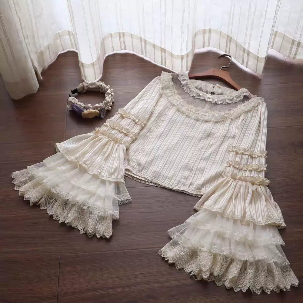 Natural-colour vertically striped blouse with lace collar and layered sleeves laid flat.