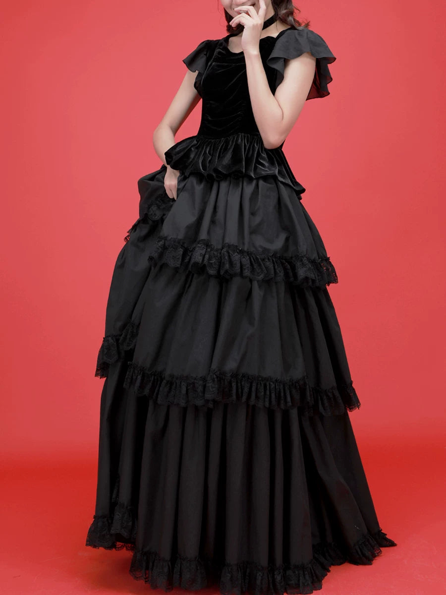 Black tiered top and full skirt with lace-edged ruffles on a red studio backdrop.