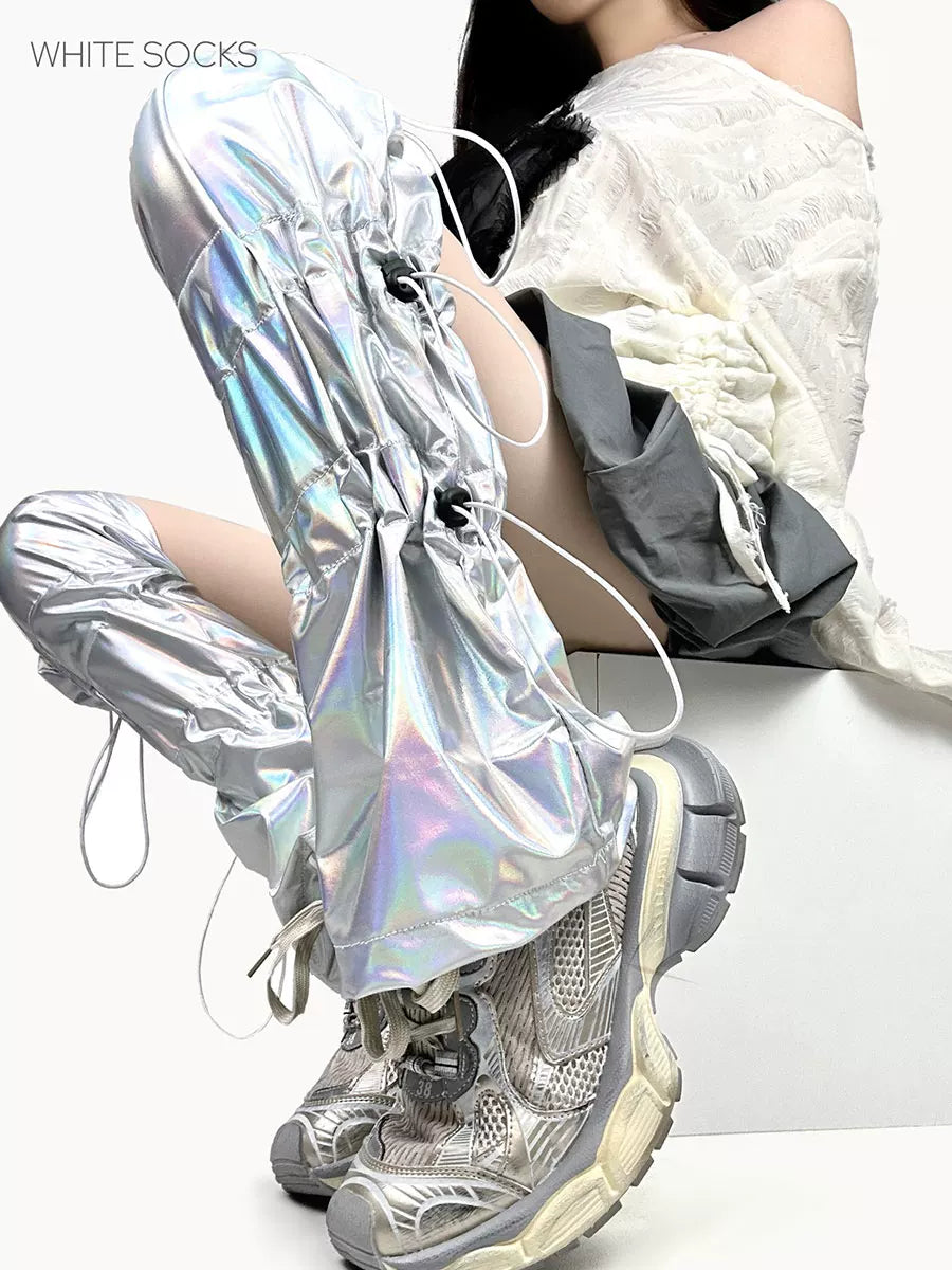 Silver holographic leg warmers with drawstrings worn over pointed shoes.