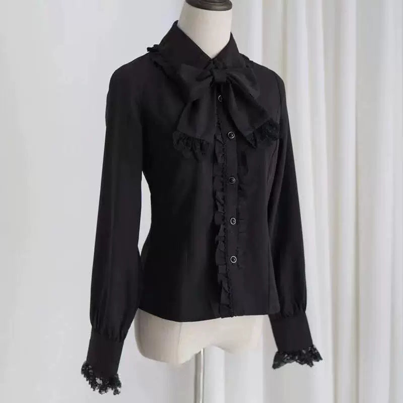 White and black long-sleeve blouses with doll collars and neck bows on mannequins.