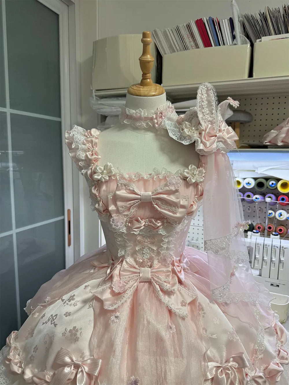 Pink floral JSK with layered lace trim and bows displayed on a dress mannequin.