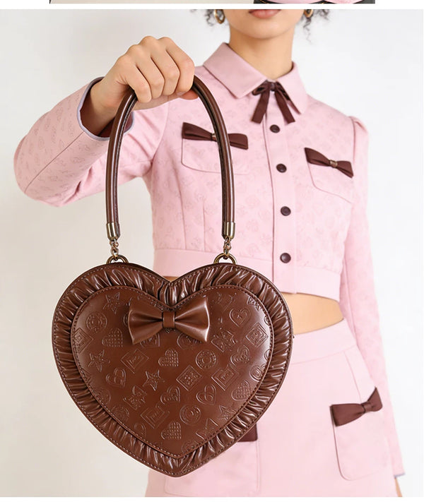 Pink heart-shaped bag with a central bow and embossed motifs.