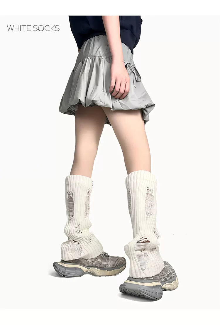 White ribbed slouch leg warmers with distressed openings worn over grey sneakers