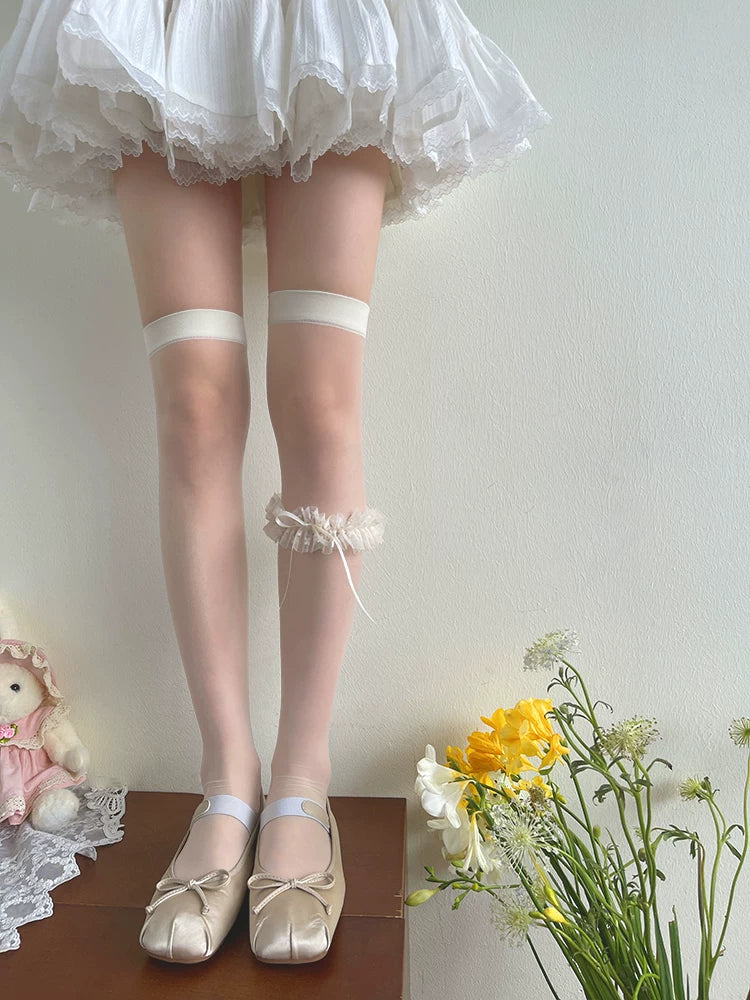 White and black over-the-knee stockings styled with lace bow leg rings and black shoes.